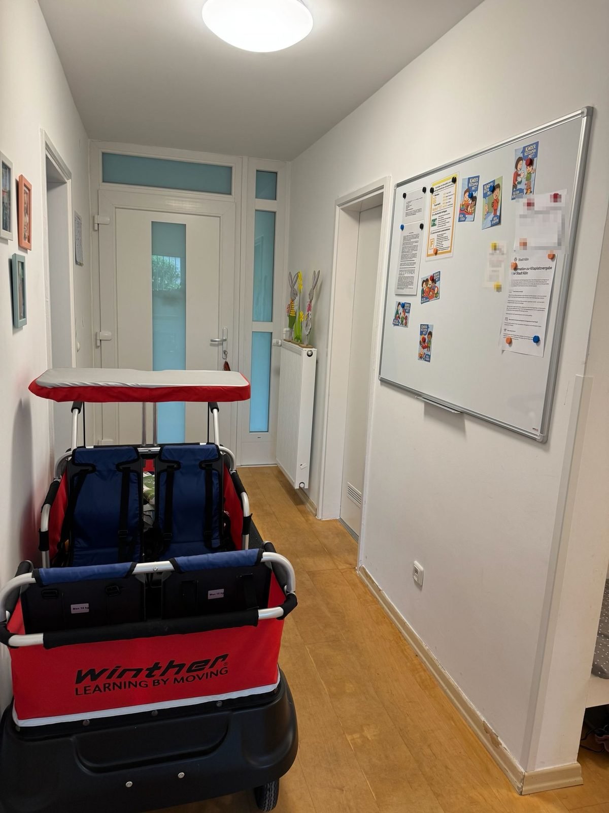 Eingangsbereich mit Krippenwagen und Infotafel für Eltern