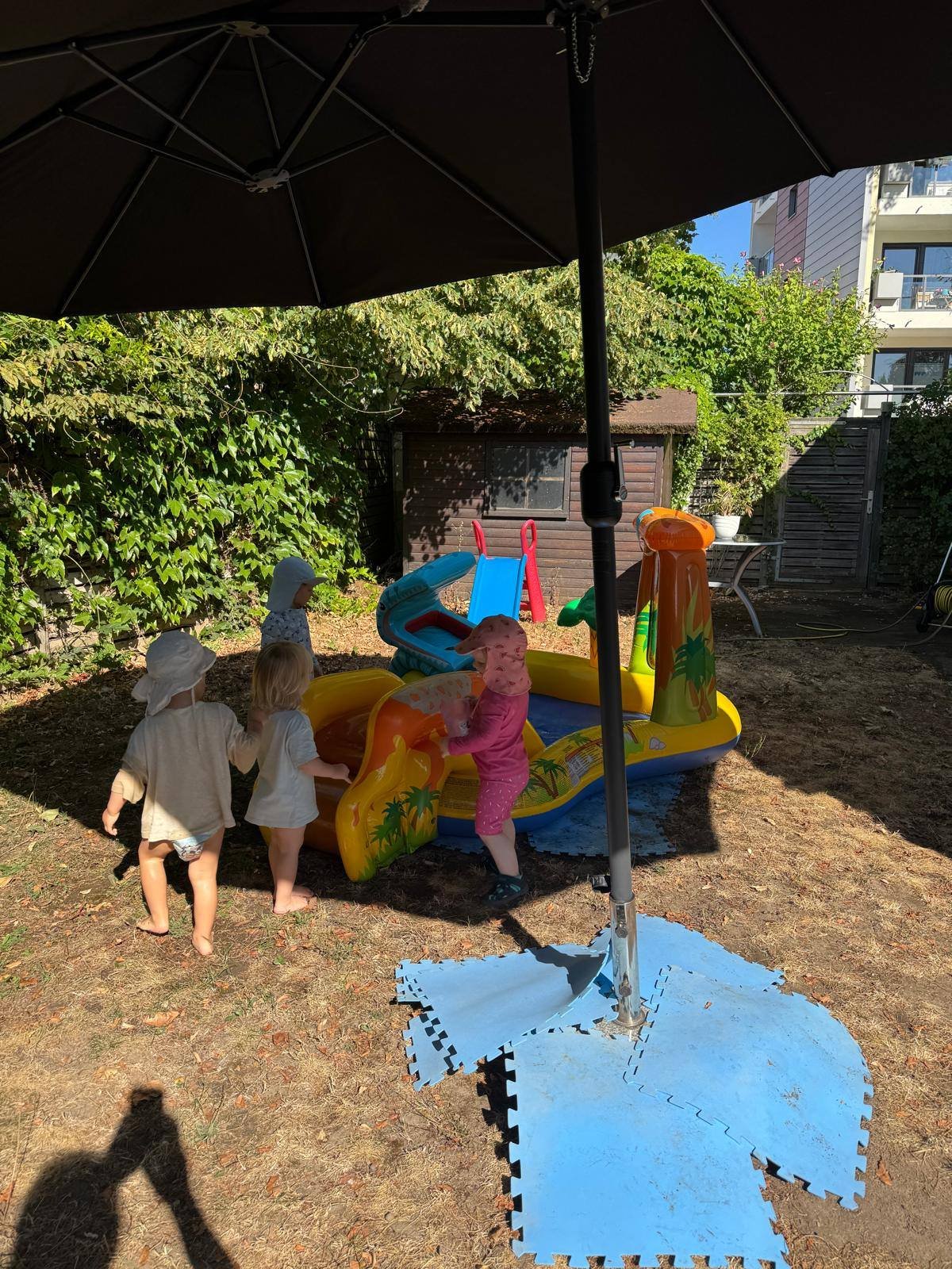 Kinder spielen im Sommer am Planschbecken im schattigen Garten