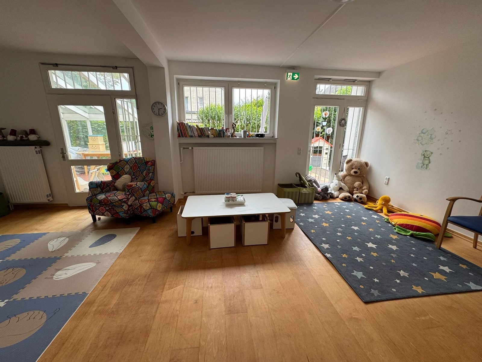 Heller Wohn- und Spielbereich mit Sternenteppich und Kuscheltieren